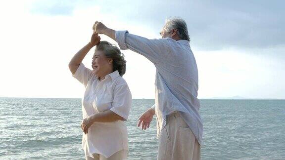 浪漫的亚洲老年夫妇在海滩上跳舞的慢动作