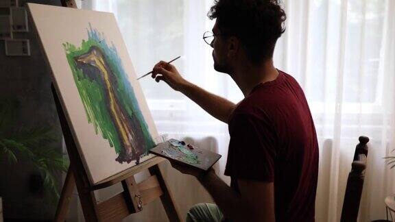 坚定的现代年轻男性艺术家在他的家庭艺术工作室绘画