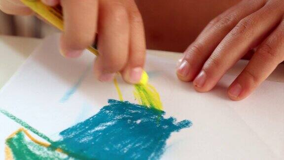用蜡笔在纸上画画的孩子的手特写儿童用黄色蜡笔手绘