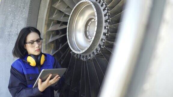 女飞机工程师在机场用数码平板检查喷气发动机