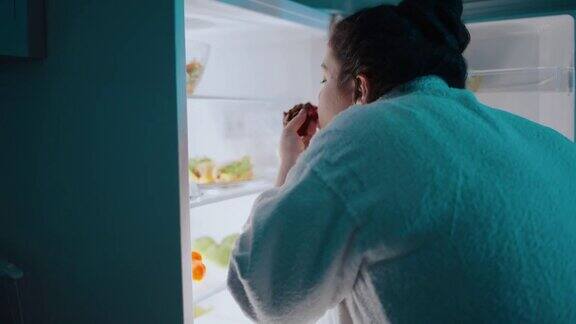 饥饿肥胖的女人晚上从冰箱里拿食物强迫性暴饮暴食