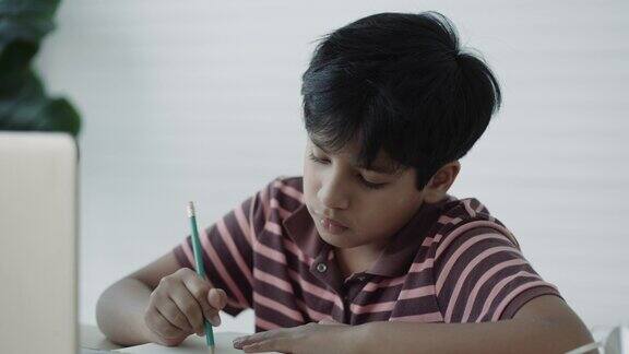 亚洲男孩使用笔记本电脑在家里在线学习