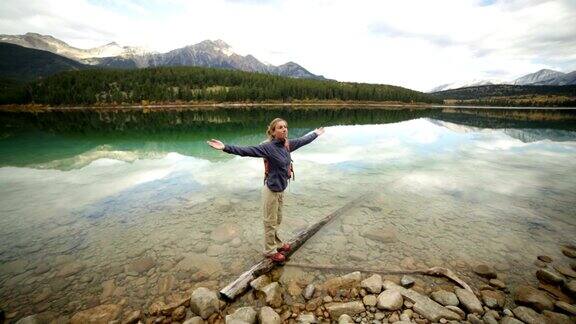 年轻女子在木头上保持平衡手臂伸在湖面上