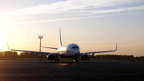 一架白色的大飞机准备起飞在日落时分开始在跑道上移动