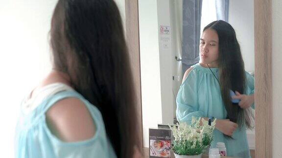 一个年轻女子早晨在镜子前梳头发
