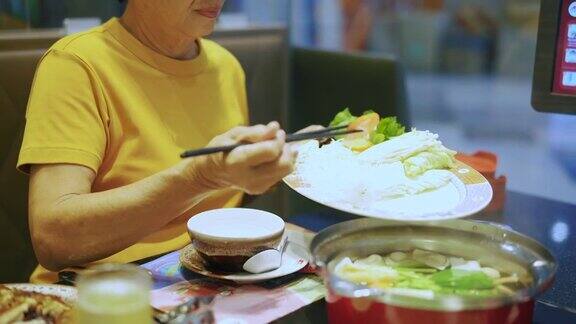 年长的女人吃着素食涮锅