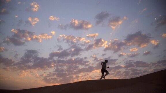 日出时沿着沙丘慢跑的跑步者