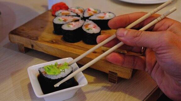 在餐馆里用筷子吃卷盘子里放一份寿司姜芥末蘸酱油