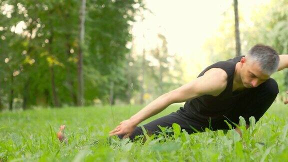 在绿色草地上做瑜伽动作和姿势的运动者瑜伽修行者平衡腿缓慢移动的手臂