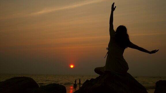 日落时分在海滩上练习瑜伽的女孩
