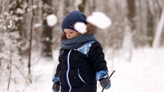 小男孩在白雪覆盖的森林里玩棍子