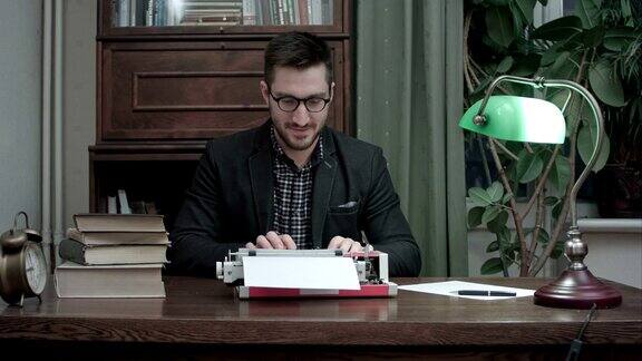 戴着眼镜的年轻作家搓着手开始在一台红色老式打字机上打字