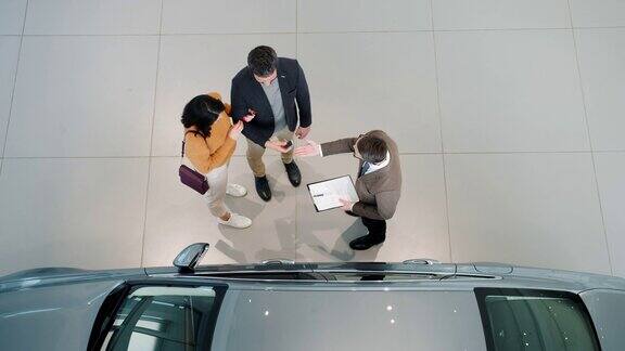 俯视图的汽车买家握手与经销商拥抱在室内经销商