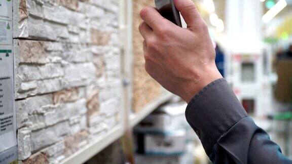 一名男子拿着智能手机在商店挑选装修房子的材料