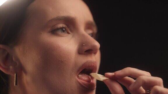 美女在摄影棚里吃了一口美味的薯片舔了舔手指