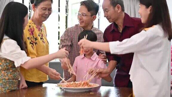 一个亚洲家庭在团圆饭期间用传统食物“生鱼”庆祝中国新年