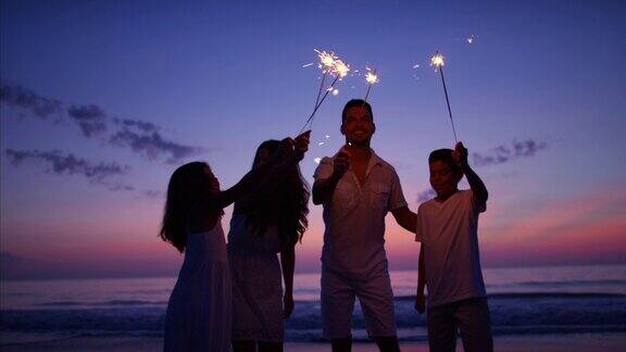 夕阳西下的西班牙家庭在海滩上用烟花