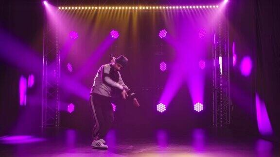 一个霹雳舞舞者在一个黑暗的演播室与明亮的动态霓虹灯的情感表演体育生活方式慢动作