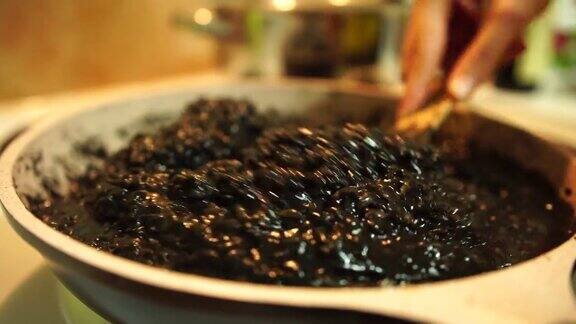 用锅铲在炉子上搅拌黑色调味饭用米饭做黑烩饭