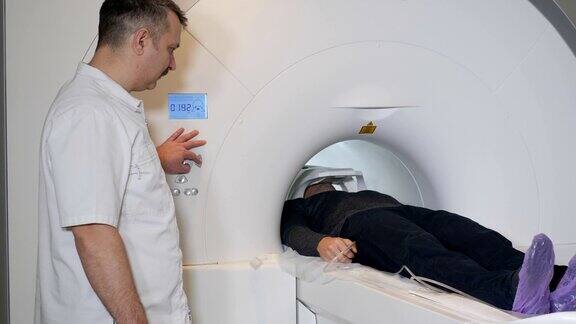 男性病人正在进行ct扫描医疗设备:诊断门诊用计算机体层摄影机健康医生按下CTMRI扫描仪设置按钮高清