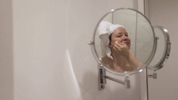 一瓶保湿面部皮肤的血清健康和美容化妆品浴室里的女人在脸上涂抹化妆品