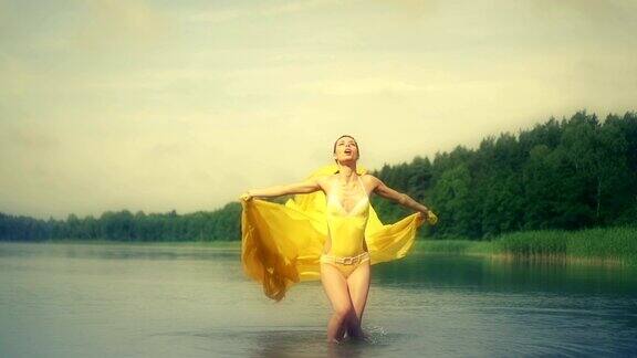拿着黄色围巾在水里跳的女人