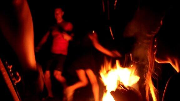 晚上欢快的朋友们在篝火旁弹着吉他跳舞唱着有趣的歌曲