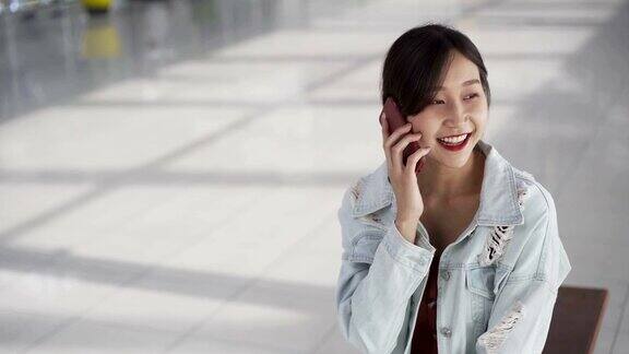 年轻的亚洲女性在机场触摸智能手机准备旅行