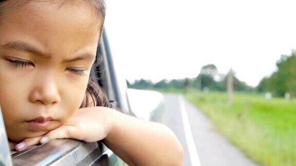 悲伤可爱的亚洲小女孩看着窗外的乡村慢镜头