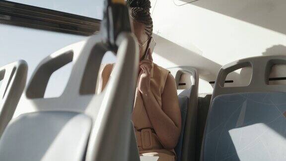 一个年轻女商人在乘坐公交车时使用智能手机和笔记本电脑的4k视频片段