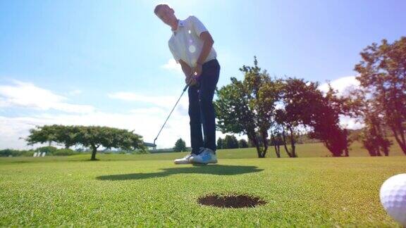 高尔夫球手试图把球打进草地上的洞里高尔夫球场上的高尔夫球手