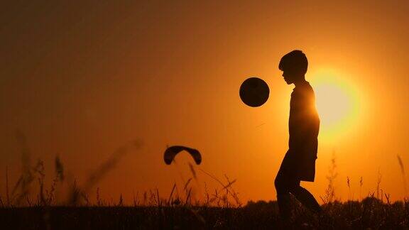 一个男孩的剪影踢足球或足球在美丽的日落背景的海滩童年宁静运动生活理念