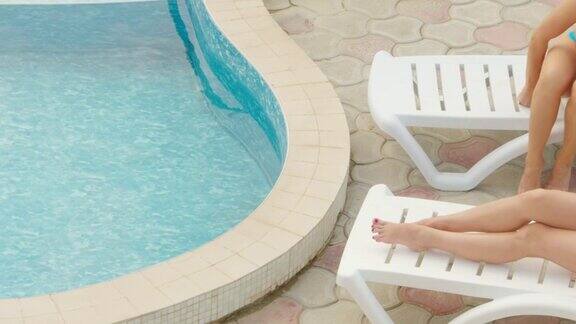 裸腿躺在泳池边的日光浴躺椅上