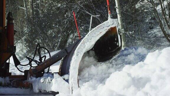 一辆橙色的拖拉机在深雪中犁地然后消失在雪堆后面