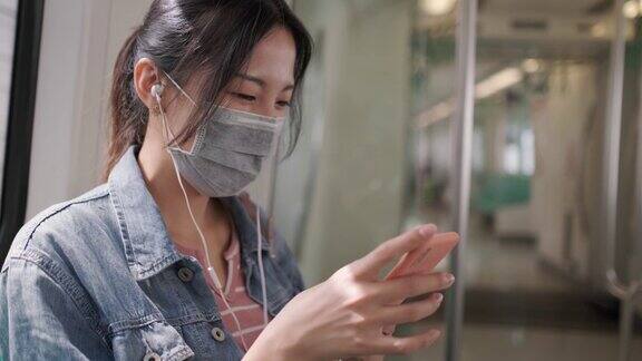 亚洲女性在乘坐地铁或火车时会戴口罩、使用智能手机和耳机并保持社交距离