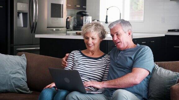 老年夫妇在家里的沙发上使用笔记本电脑