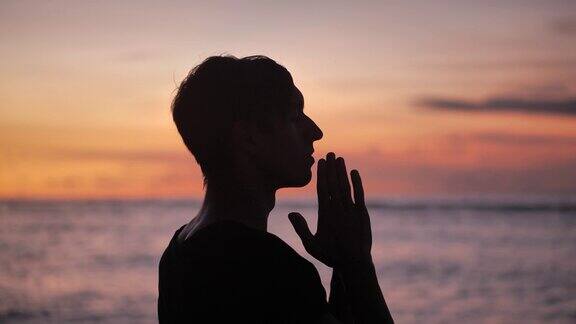 一个男人在日落时祈祷的剪影宗教轮廓的人接近