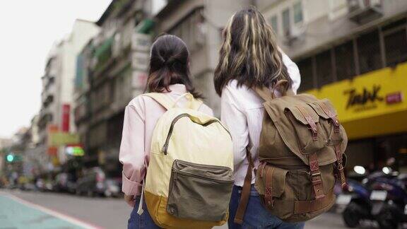 两个背着背包的学生在街上的后视图
