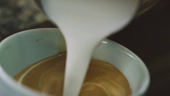 一个人小心地把蒸牛奶倒进咖啡里然后制作拉花艺术