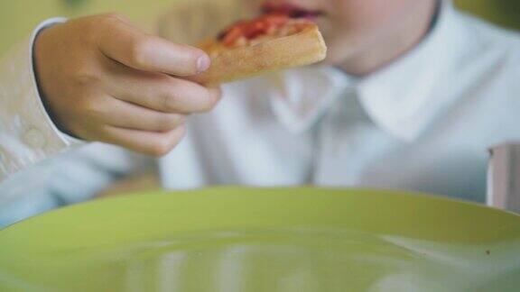 穿衬衫的男孩午餐与新鲜的披萨在桌子近距离