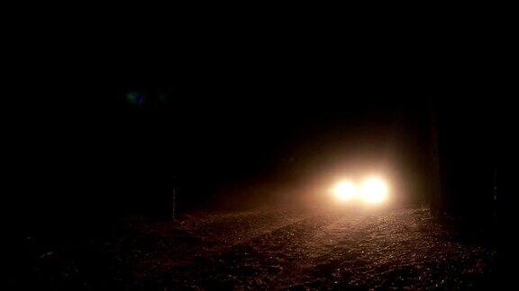 在黑暗的道路上一辆汽车的前灯向我们驶来