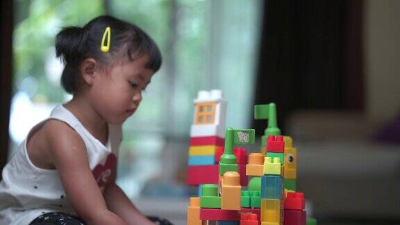 可爱的小女孩在家里玩塑料积木