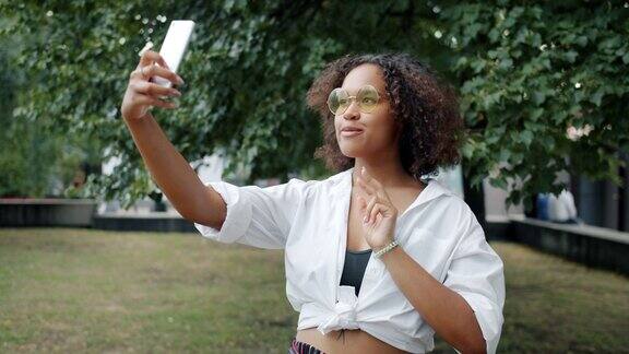 非裔美国女孩在城市公园用智能手机自拍
