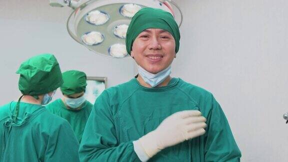 医院手术室的一组医生多元化的团队亚洲专业的外科医生和护士缝合手术成功后感到高兴和鼓掌男人微笑着摘下面具