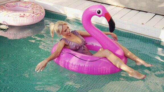 一个年轻的女人在一个充气的粉红色火烈鸟上游泳