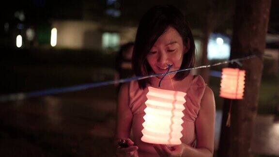亚洲华人妇女在纸灯笼里点燃蜡烛庆祝节