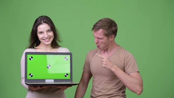 年轻的幸福夫妇展示笔记本电脑和得到好消息在一起