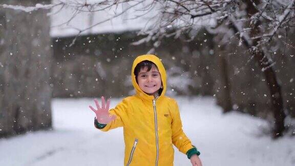 穿着黄色冬衣的滑稽小男孩在下雪时行走儿童冬季户外活动