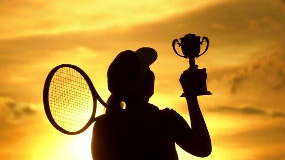 一个羽毛球运动员庆祝赢得比赛在日落剪影