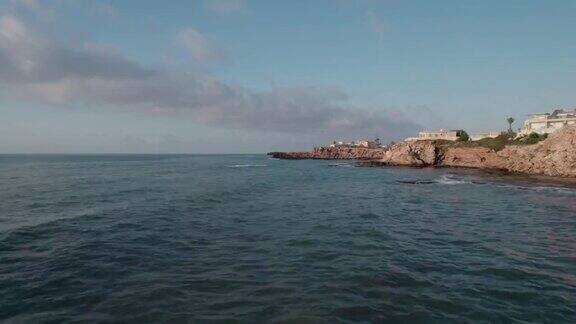 日出在岩石海岸摄像机慢慢地向侧面移动海浪撞击着岩石